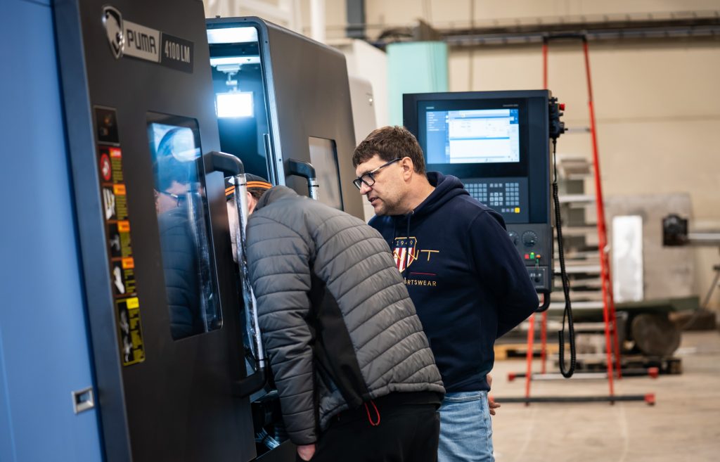 Hallissa kurkistetaan upouuden investoinnin sisään ja tutkaillaan laitteen ohjaimistoa operaattorin kanssa. Yrityksen kattava konekanta mahdollistaa nopean reagoinnin asiakkaiden tarpeisiin.